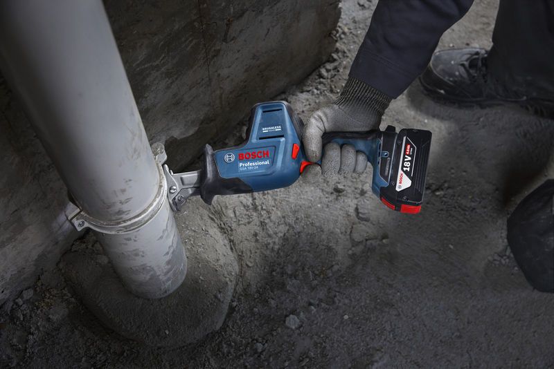 GSA 18V-24 Một người mặc đồ bảo hộ đang cắt ống nhựa bằng cưa lọng.