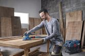 Người đeo thiết bị an toàn chà nhám mặt bàn gỗ bằng máy chà nhám quỹ đạo.