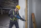 Một người mặc đồ bảo hộ đang cắt xuyên qua thanh tường bằng cưa lọng.
