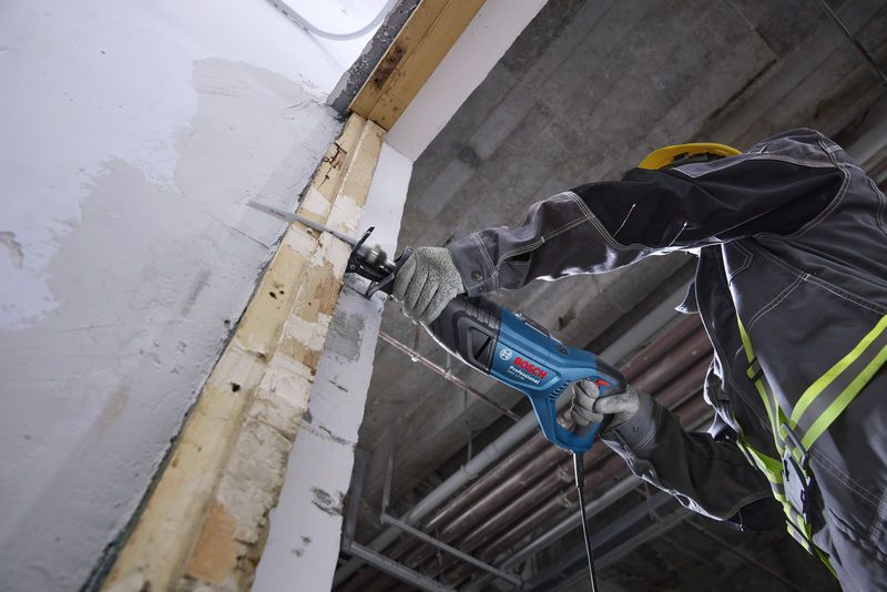 GSA 12-30 Một người mặc đồ bảo hộ đang sử dụng máy cưa lọng để cắt vào tường.