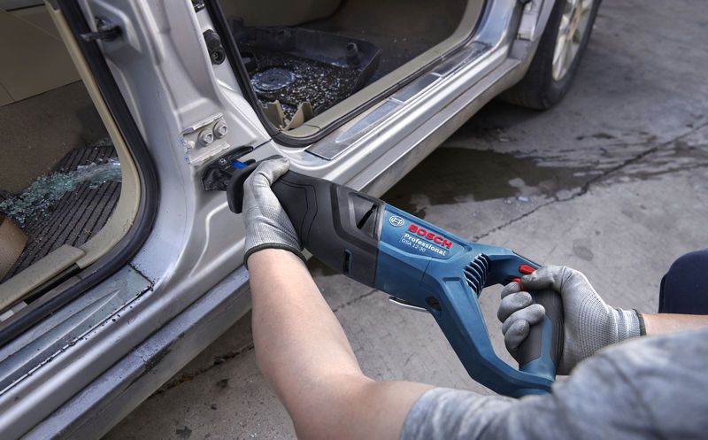 GSA 12-30 Một người mặc thiết bị an toàn đang sử dụng cưa lọng để cắt kim loại trên khung cửa ô tô.