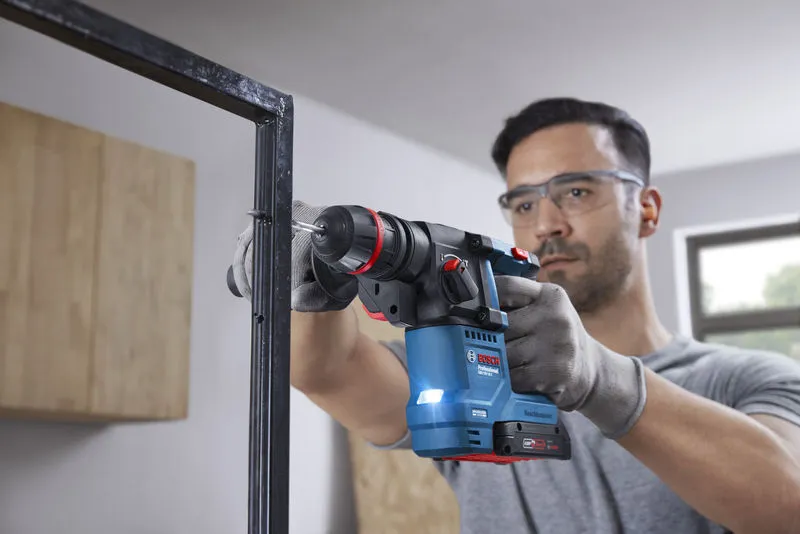 GBH 18V-18 X Một người mặc đồ bảo hộ sẽ khoan vào khung kim loại bằng máy khoan búa không dây.
