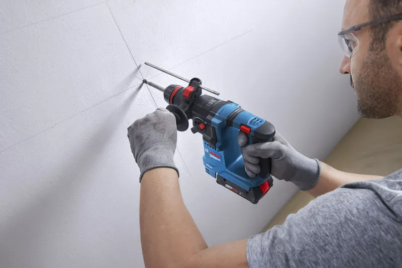 GBH 18V-18 X Một người mặc đồ bảo hộ sẽ khoan lỗ vào bức tường đã đánh dấu bằng búa quay không dây.