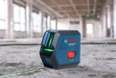 Máy cân bằng laser chiếu các đường màu xanh lá cây trên sàn bê tông tại công trường xây dựng.