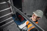 Một người mặc thiết bị an toàn đang gắn đèn công trường không dây vào một ống kim loại.