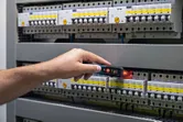 Người đang kiểm tra bảng điện bằng máy kiểm tra điện áp không tiếp xúc.