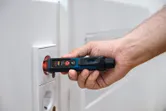 Một người sử dụng máy kiểm tra điện áp không tiếp xúc gần ổ cắm điện.
