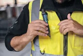 Người đeo thiết bị an toàn đặt máy kiểm tra điện áp không tiếp xúc vào túi áo vest.