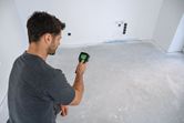 Một người đang quét sàn phòng trống bằng camera nhiệt cầm tay.