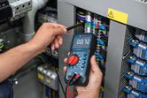 Người ta đo điện áp trên bảng điện bằng đồng hồ vạn năng kỹ thuật số.