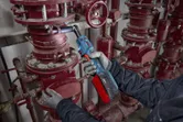 Một người mặc đồ bảo hộ đang siết chặt bu lông ống bằng cờ lê không dây.