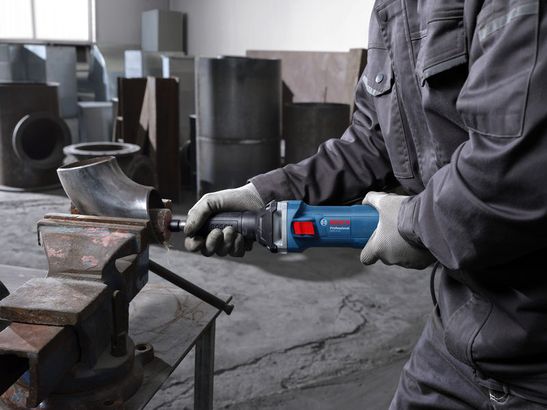 GGS 5 LS Một người mặc thiết bị an toàn đang mài một ống kim loại được kẹp trong ê tô.