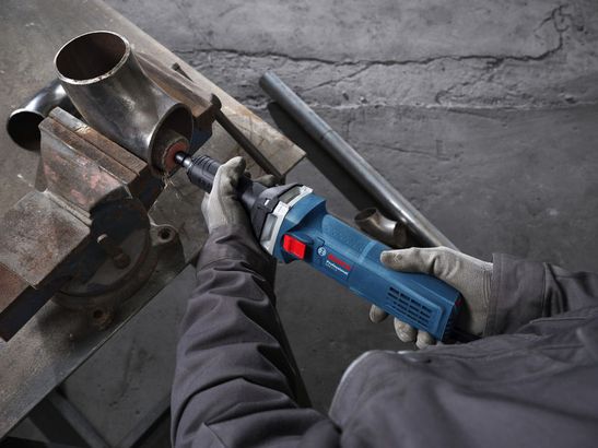 GGS 5 LS Một người mặc đồ bảo hộ đang mài bên trong ống kim loại bằng máy mài góc.