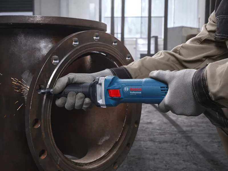 GGS 5 LS Một người mặc đồ bảo hộ đang mài một ống kim loại bằng máy mài thẳng.