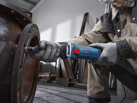 GGS 5 LS Một người mặc đồ bảo hộ đang đánh bóng một mặt bích kim loại lớn bằng máy mài góc.