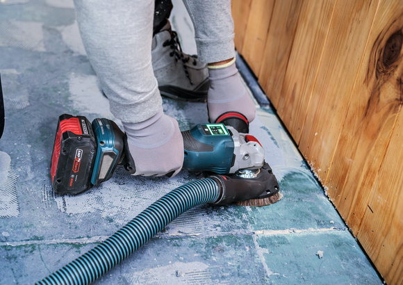 Object #200557588: 7425288_APP_WIDE_1 Một người mặc đồ bảo hộ đang chà nhám sàn bê tông gần bức tường gỗ.