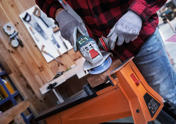 Object #200557592: 7425288_APP_WIDE_5 Người đeo thiết bị an toàn sử dụng máy mài góc để chà nhám gỗ được kẹp vào bàn làm việc.