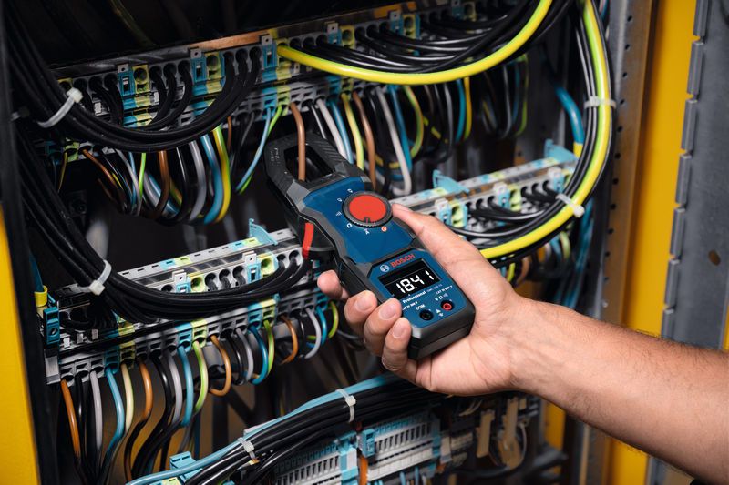 Một người sử dụng ampe kìm để đo dòng điện trong bảng điều khiển điện.