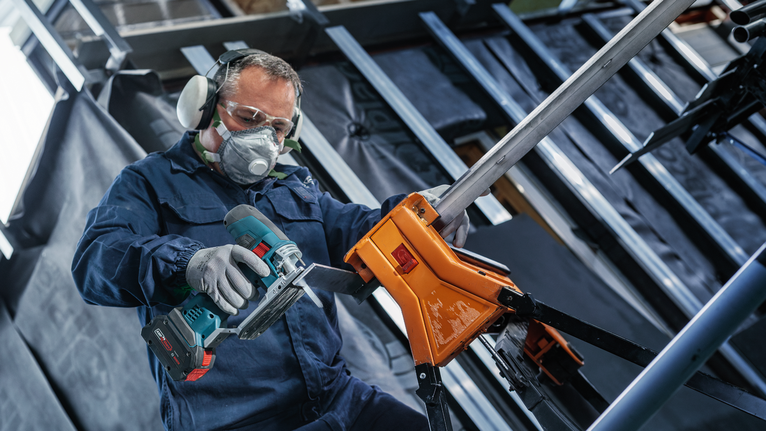 Lưỡi cưa lọng EXPERT Tough Metal thick T155HHM, 3 chiếc Một người mặc đồ bảo hộ đang cắt ống kim loại bằng dụng cụ điện không dây.