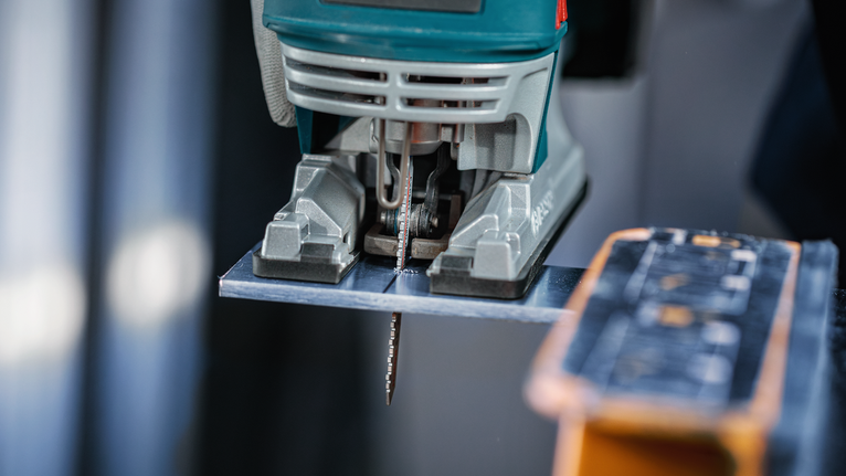 Lưỡi cưa lọng EXPERT Tough Metal thick T155HHM, 3 chiếc Máy cưa lọng đang cắt tấm kim loại trên bàn làm việc.