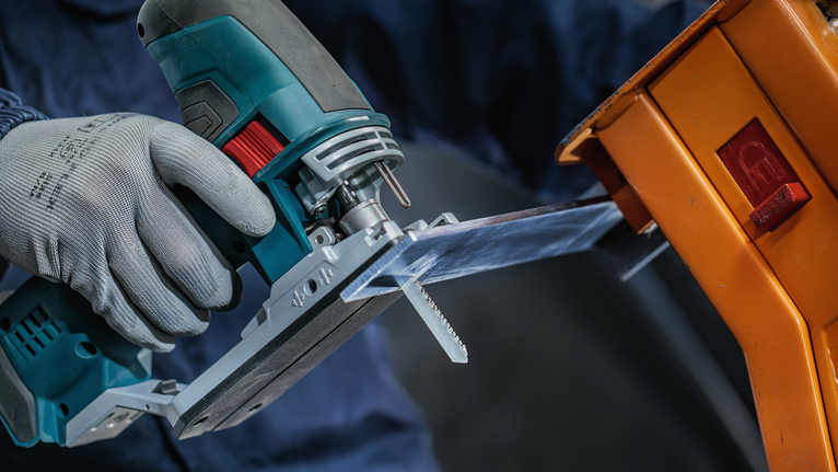 Lưỡi cưa lọng EXPERT Tough Metal thick T155HHM, 3 chiếc Một người mặc đồ bảo hộ sử dụng máy cưa lọng để cắt một tấm nhựa trong suốt.