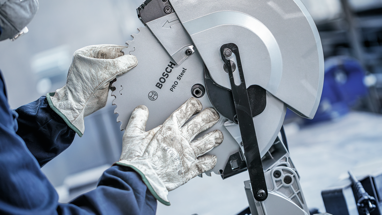 Người đeo thiết bị an toàn đang điều chỉnh lưỡi cưa tròn.