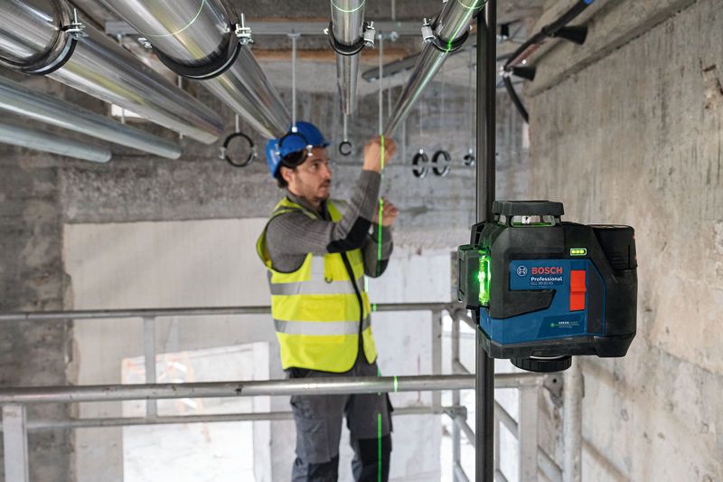 Một người mặc thiết bị an toàn đang căn chỉnh các đường ống bằng dụng cụ cân bằng laser.