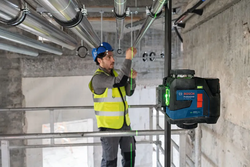 Một người mặc thiết bị an toàn đang căn chỉnh các đường ống bằng dụng cụ cân bằng laser.