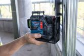 Một người đang giữ một dụng cụ cân bằng laser trên một thanh kim loại trong khu vực đang xây dựng.