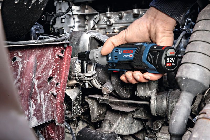 Một người sử dụng cờ lê không dây để siết chặt bu lông trên động cơ.