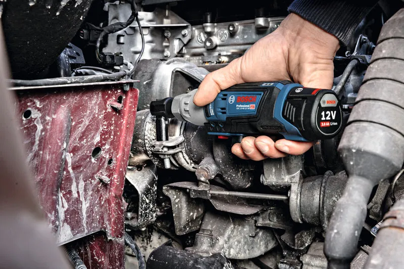 Một người sử dụng cờ lê không dây để siết chặt bu lông trên động cơ.