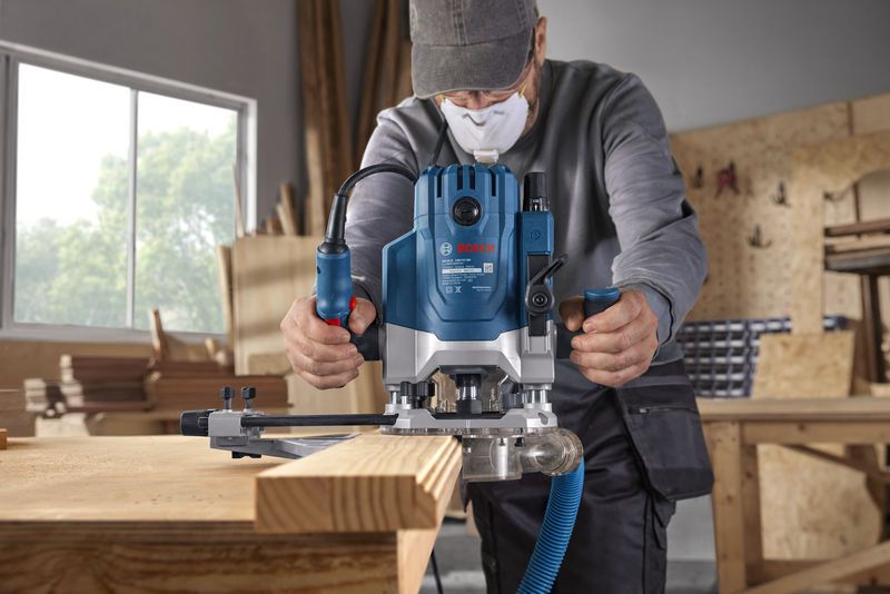 GOF 20-12 Một người mặc đồ bảo hộ sử dụng máy phay để định hình cạnh của một tấm ván gỗ.