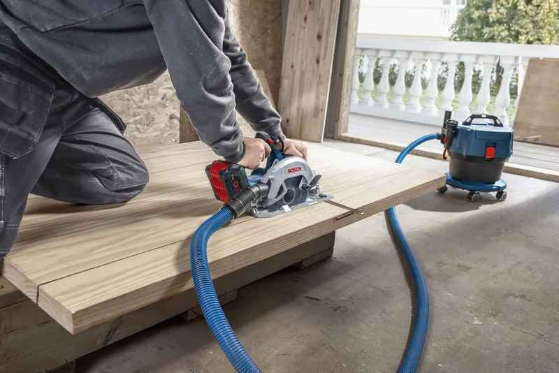 Một người đang cắt gỗ bằng máy cưa tròn không dây được kết nối với máy hút bụi.