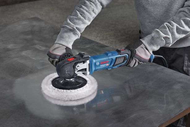 GPO 14-180 S Một người mặc đồ bảo hộ đang đánh bóng tấm kim loại bằng máy đánh bóng điện.