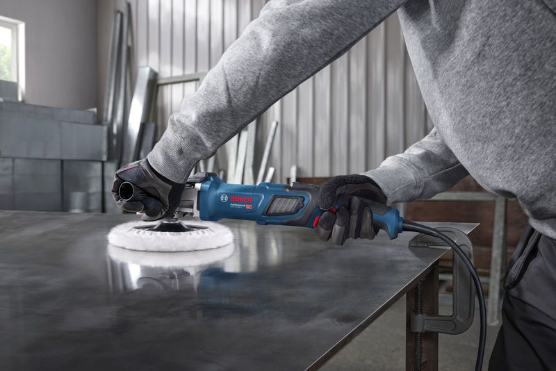 GPO 14-180 S Một người mặc đồ bảo hộ đang đánh bóng tấm kim loại bằng dụng cụ điện màu xanh.