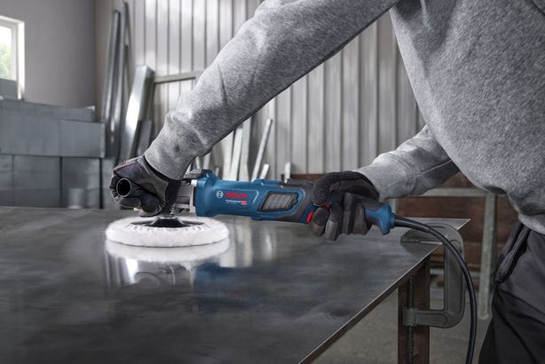 GPO 14-180 S Một người mặc đồ bảo hộ đang đánh bóng tấm kim loại bằng dụng cụ điện màu xanh.