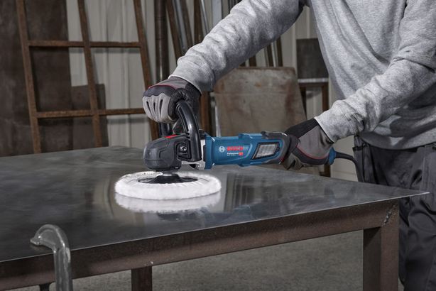 GPO 14-180 S Một người mặc đồ bảo hộ đang sử dụng máy đánh bóng trên bề mặt kim loại.