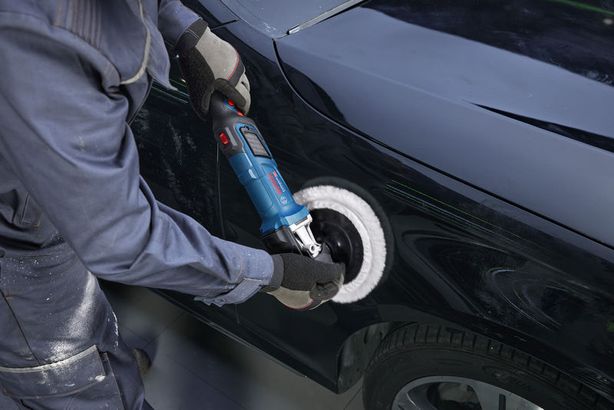 GPO 14-180 S Một người mặc đồ bảo hộ đang đánh bóng cửa ô tô bằng máy đánh bóng điện.