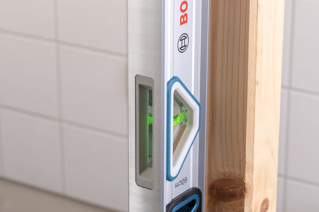 Thước thủy dùng để đo độ thẳng đứng của một thanh gỗ.