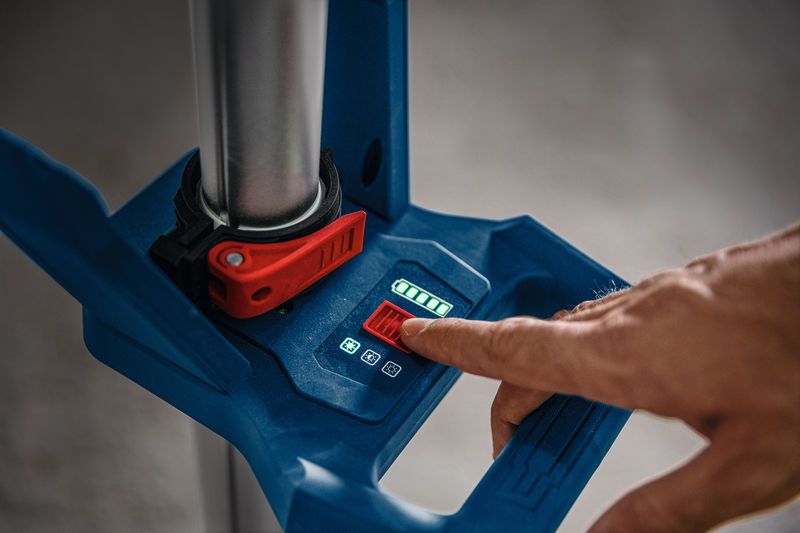 Một người đang điều chỉnh đèn công trường không dây bằng bảng điều khiển kỹ thuật số.