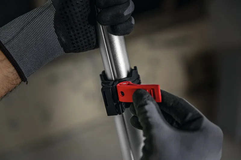 Một người mặc thiết bị an toàn đang điều chỉnh kẹp màu đỏ trên một cột kim loại.