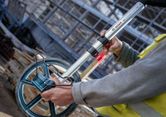 Một người đeo thiết bị an toàn đo khoảng cách bằng một bánh xe đo lớn.