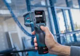 Người vận hành máy dò nhiệt có màn hình hiển thị kỹ thuật số tại công trường xây dựng.