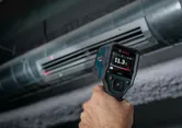 Người sử dụng máy đo nhiệt để đo nhiệt độ không khí tại cửa gió của hệ thống HVAC.
