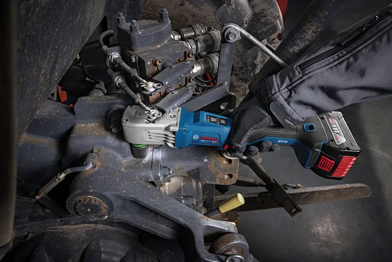 Một người đàn ông mặc đồ bảo hộ đang sử dụng máy siết bu lông không dây trên máy móc.