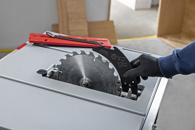 Một người đàn ông mặc đồ bảo hộ đang thay lưỡi cưa bàn.