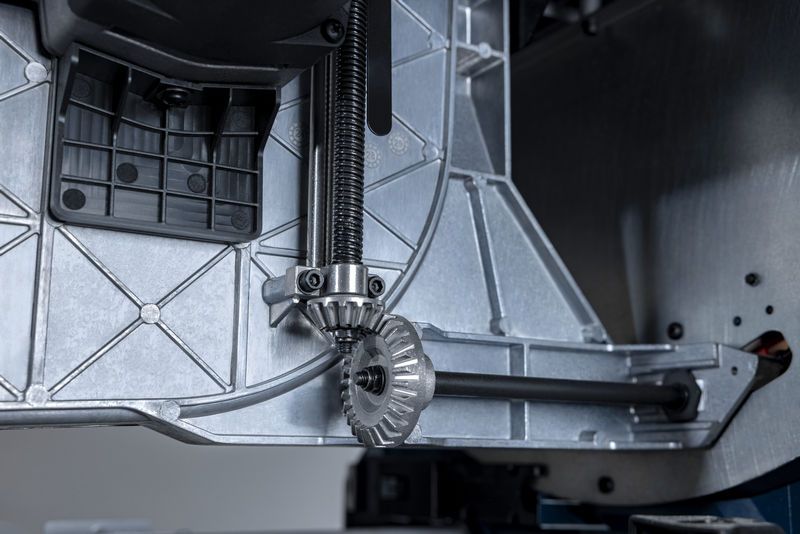 Ảnh cận cảnh cơ cấu bánh răng kim loại bên trong đế máy cưa bàn.