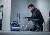 Một người mặc đồ bảo hộ đang kiểm tra đường ống nước bằng máy nén khí di động.