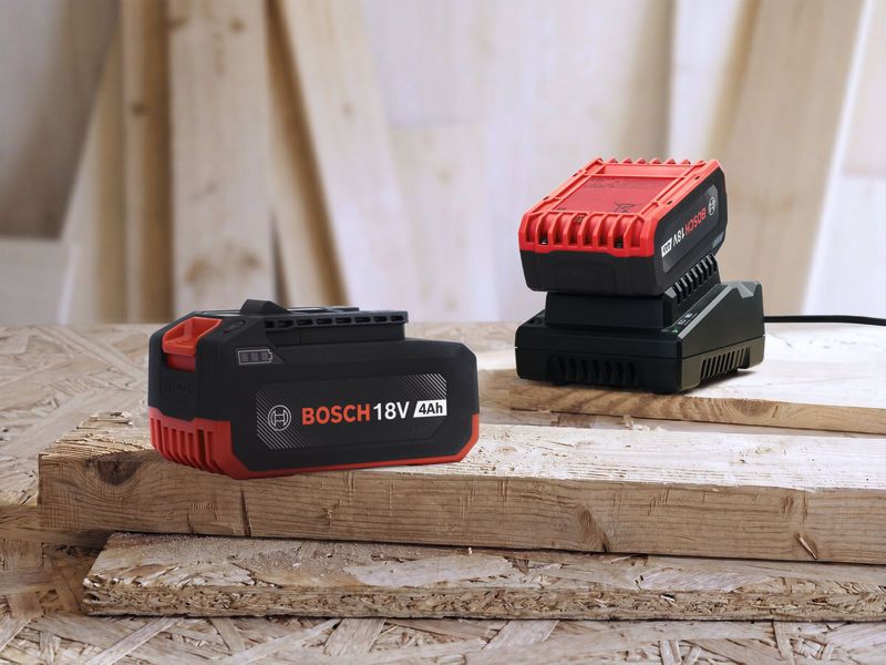 Pin sạc và bộ sạc của dụng cụ điện cầm tay được đặt trên các tấm ván gỗ xếp chồng lên nhau.