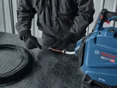 Một người mặc đồ bảo hộ đang đưa dây vào máy kéo cáp.